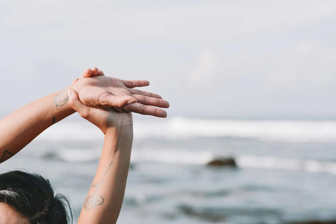 Hands raised and clasped overhead against a blurred sea horizon